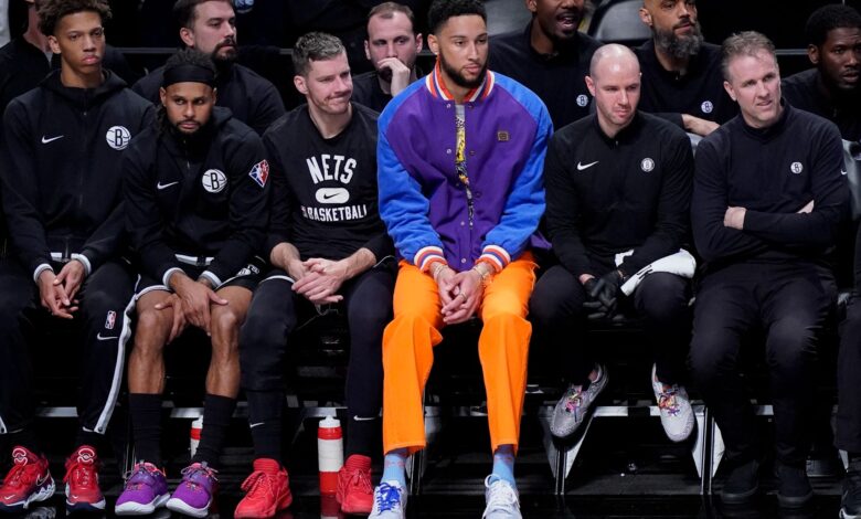 Ben Simmons sitting courtside at a basketball game, brooklyn nets and celtics game, outfit orange pants, purple jacket, nba 2022 finals